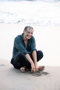 Young man sitting on sand at beach