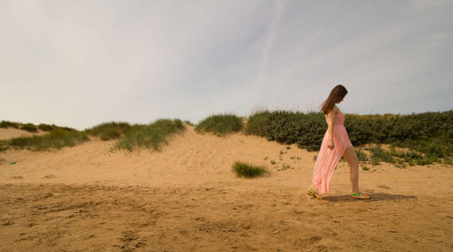 Woman standing on sand at beach against sky