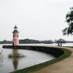 Lighthouse by grass against sky