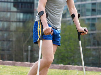 Midsection of man with crutches walking at park