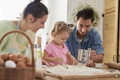 Father by mother and daughter preparing food in kitchen