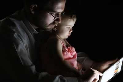Father with baby girl using digital tablet in darkroom