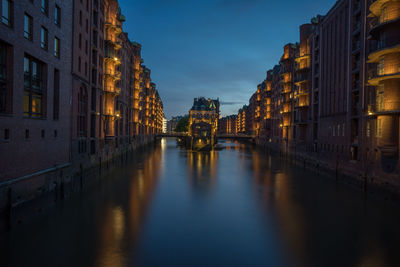 Canal amidst buildings in city at dusk