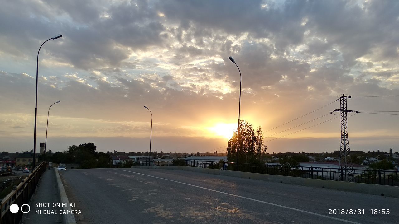 CARS ON STREET AGAINST SKY DURING SUNSET