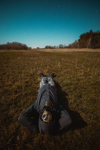 Person in the gas mask laying on the ground and watching the sky.