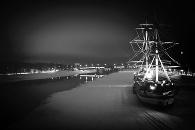 Cars on illuminated harbor against sky at night