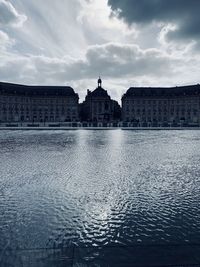 Buildings in city against cloudy sky