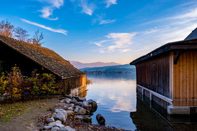 House by lake against sky