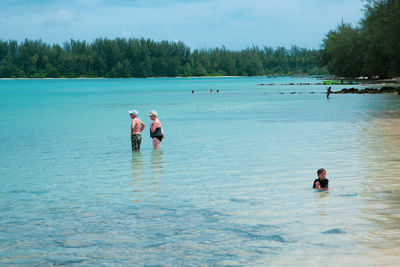 People swimming in sea against sky