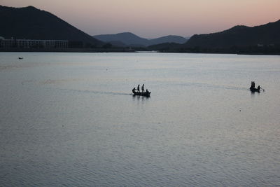 People on boat sailing in sea against sky