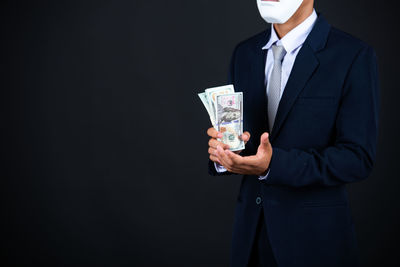 Midsection of man holding umbrella against black background