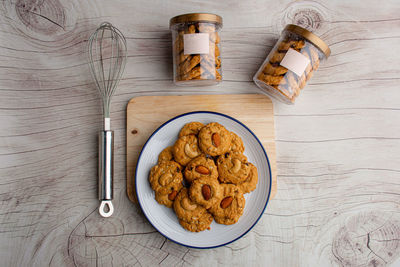 Homemade almond cookies in ceramic white plate on wood table background.