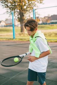 Boy playing tennis in court