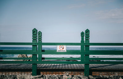 Road sign by sea against sky