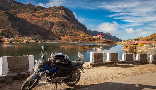 Motorcycle by lake against sky