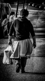 Rear view of woman walking on road