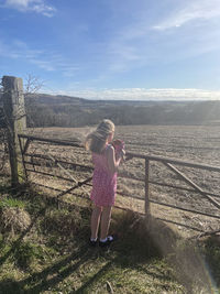 Rear view of woman standing on landscape against sky