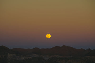 Scenic view of silhouette mountains against orange sky