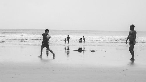 People on beach against clear sky