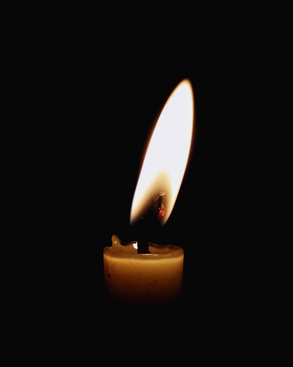 CLOSE-UP OF LIT CANDLE IN DARK