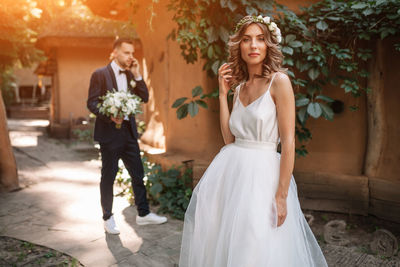 Bride and bridegroom standing by house