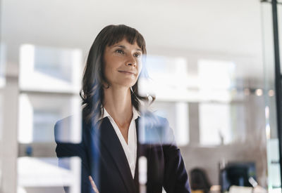 Successful businesswoman looking through glass pane