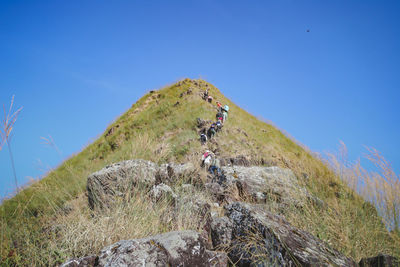 People on mountain against clear blue sky