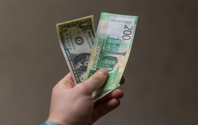 Close-up of man holding money against brown background