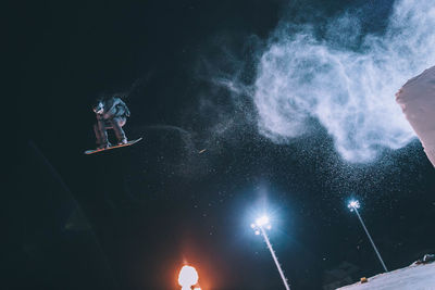 Low angle view of man snowboarding against sky at night