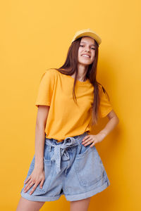 Portrait of teenager standing against yellow background