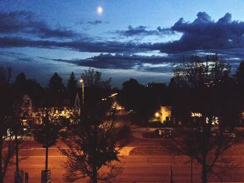 Silhouette trees on landscape against sky at night