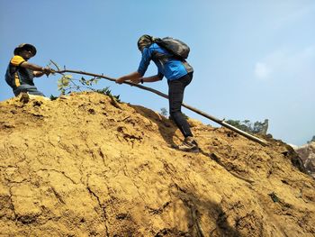 Low angle view of man on rock against sky