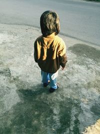 Rear view of boy walking in water