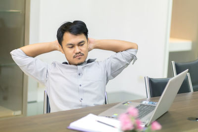 Mid adult man using mobile phone while sitting on table