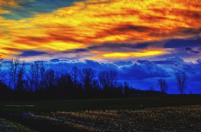 Scenic view of dramatic sky over land during sunset