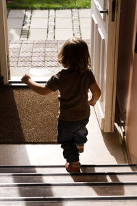 Rear view of girl walking on staircase at home