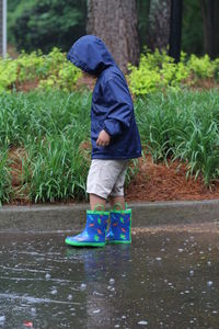 Boy wearing raincoat standing on street during rainy season