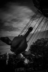 Low angle view of man hanging on rope against sky