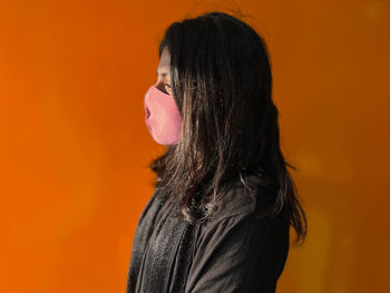 Side view of young woman against yellow background