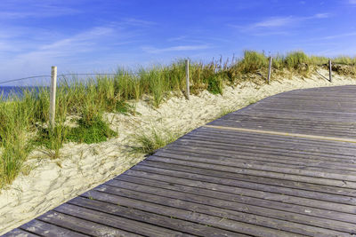 Boardwalk leading towards beach against sky