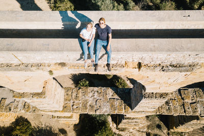High angle view of friends sitting on retaining wall