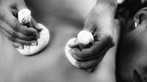 Hands of an ayurveda massage therapist pressing herbal bolus bags 