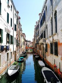 Boats moored in canal amidst buildings in city