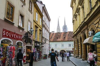 People walking on street amidst buildings in city