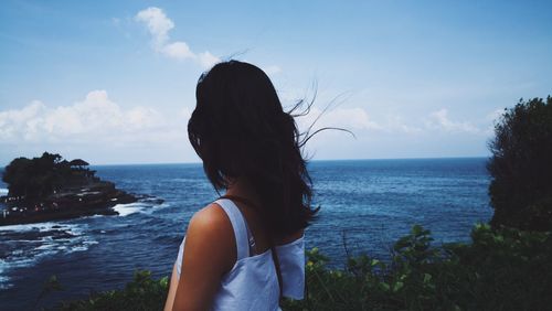 Woman standing by sea against sky