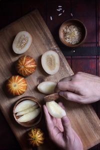 Cropped hand of man removing melon seeds over table