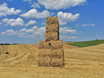 Hay bales on field against sky