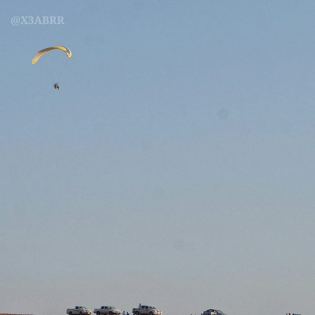 copy space, clear sky, low angle view, transportation, mode of transport, outdoors, mid-air, day, blue, flying, sky, built structure, nature, adventure, architecture, travel, no people, leisure activity, building exterior