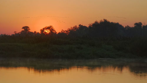 Scenic view of lake against sky at sunset