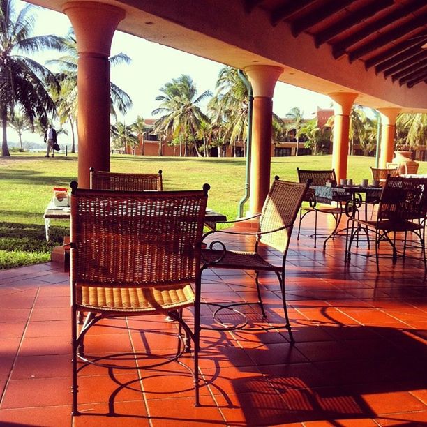 chair, table, empty, absence, tree, seat, restaurant, indoors, sunlight, bench, furniture, shadow, place setting, gazebo, sidewalk cafe, built structure, no people, park - man made space, day, wood - material